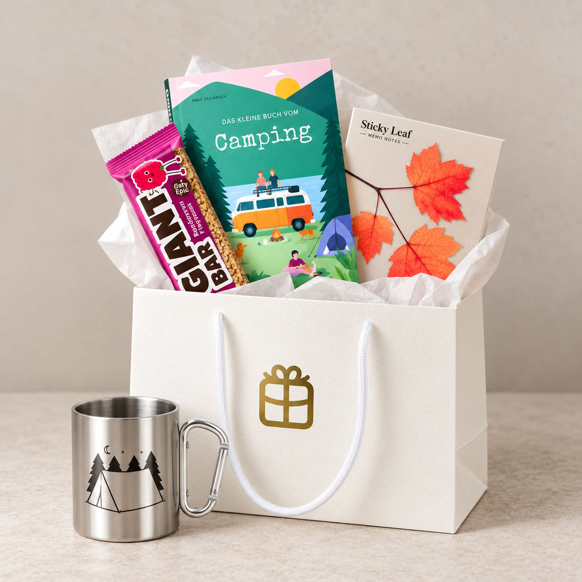 Das Pacster-„Camping Time | Geschenkset“ enthält eine weiße Geschenktüte mit Seidenpapier, ein Buch zum Thema Camping, Haftnotizen, einen Snackriegel und einen Edelstahlbecher mit Karabiner und einem Motiv aus Zelt und Bäumen – perfekte Begleiter für Ihren nächsten Campingausflug. Entdecke hochwertige Geschenkideen bei Pacster.