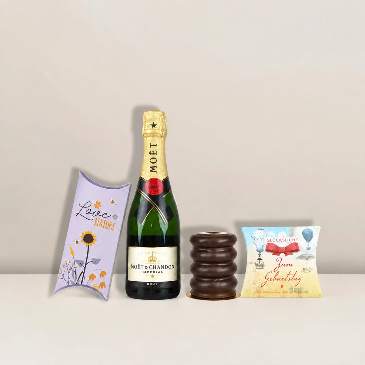 Entdecke hochwertige Geschenkideen bei Pacster. Eine Flasche Moët & Chandon Brut Impérial Champagner, ergänzt durch eine blumig gestaltete Geschenkbox, „Love Cocoa“-Milchschokoladen-Leckereien und ein Snackpaket zum Thema Geburtstag aus dem „Geburtstagsfreude | Geschenkset“ von Pacster, ist das perfekte Geschenk.