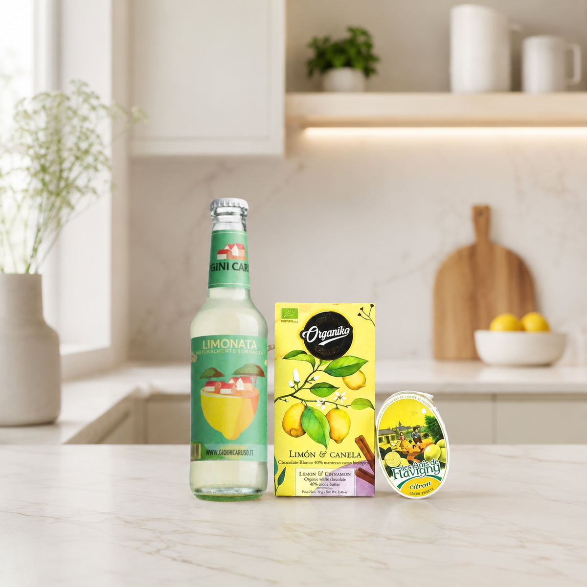 Drei Produkte rund um das Thema Zitrone aus dem Pacster-Geschenkset „Sauer macht lustig“: eine Glasflasche Bio-Zitronenlimonade, eine gelbe Schachtel mit Zitronen-Zimt-Tee und ein kleiner runder Behälter mit einem fröhlichen Zitronenmotiv. Perfekt als Geschenk oder zum Zusammenstellen einer attraktiven Geschenktüte. Entdecke hochwertige Geschenkideen bei Pacster.